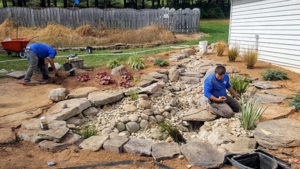 Two Pond Crew Members Pond Placing Rocks for Pond Renovation