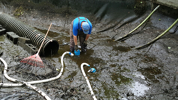 Pond Crew Member Standing In Drained Pond Pumping Water Out